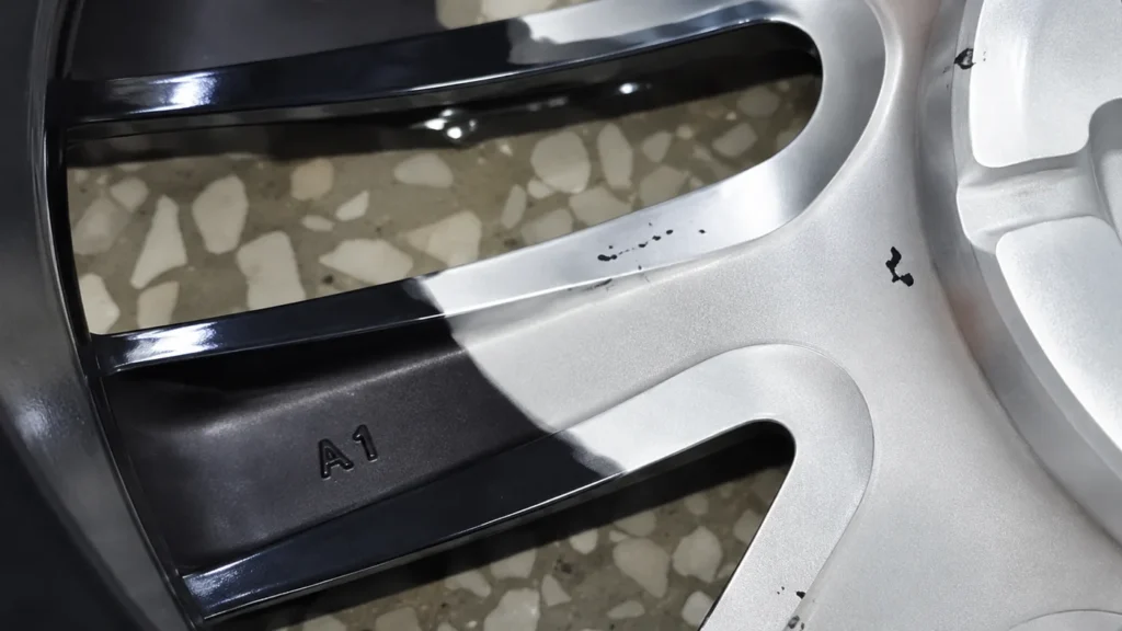 Retrait laser d’un revêtement noir sur une jante en aluminium, zone traitée et zone d’origine côte à côte