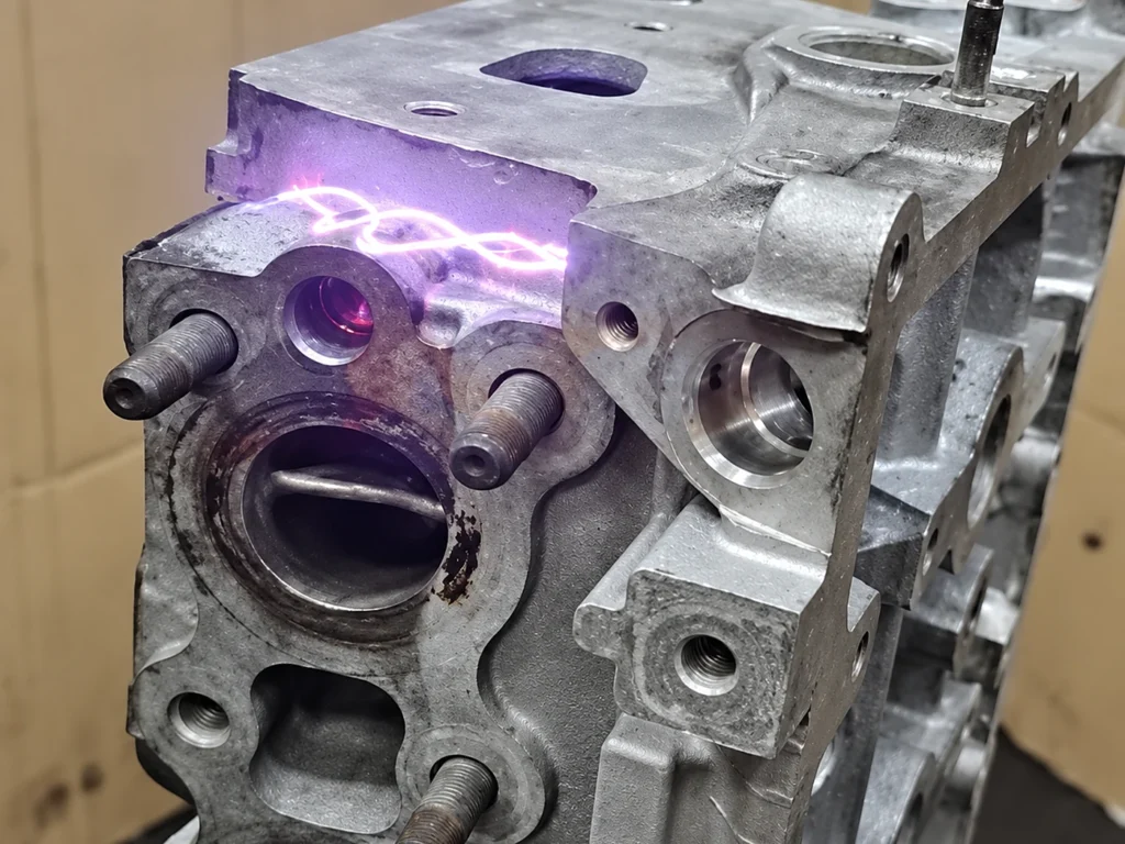 Culasse de moteur en aluminium en cours de nettoyage laser, plasma violet sur le plan de joint
